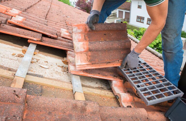 Worker On The Rooftop, Replacing Broken Tiles With New Shingles